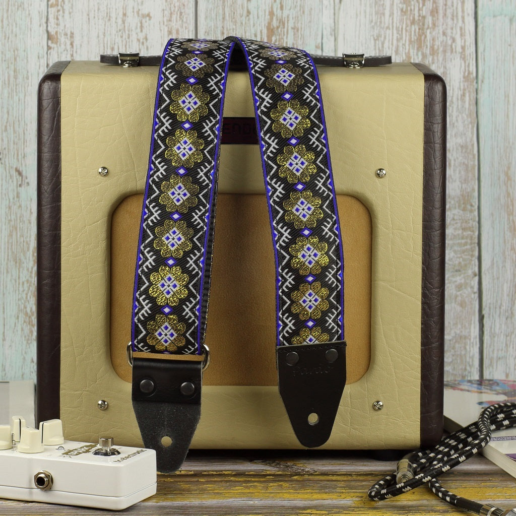 Model Daisy gold. Floral guitar strap with gold and black colors; backing black seatbelt; end leather parts color black; hardware metal color chrome