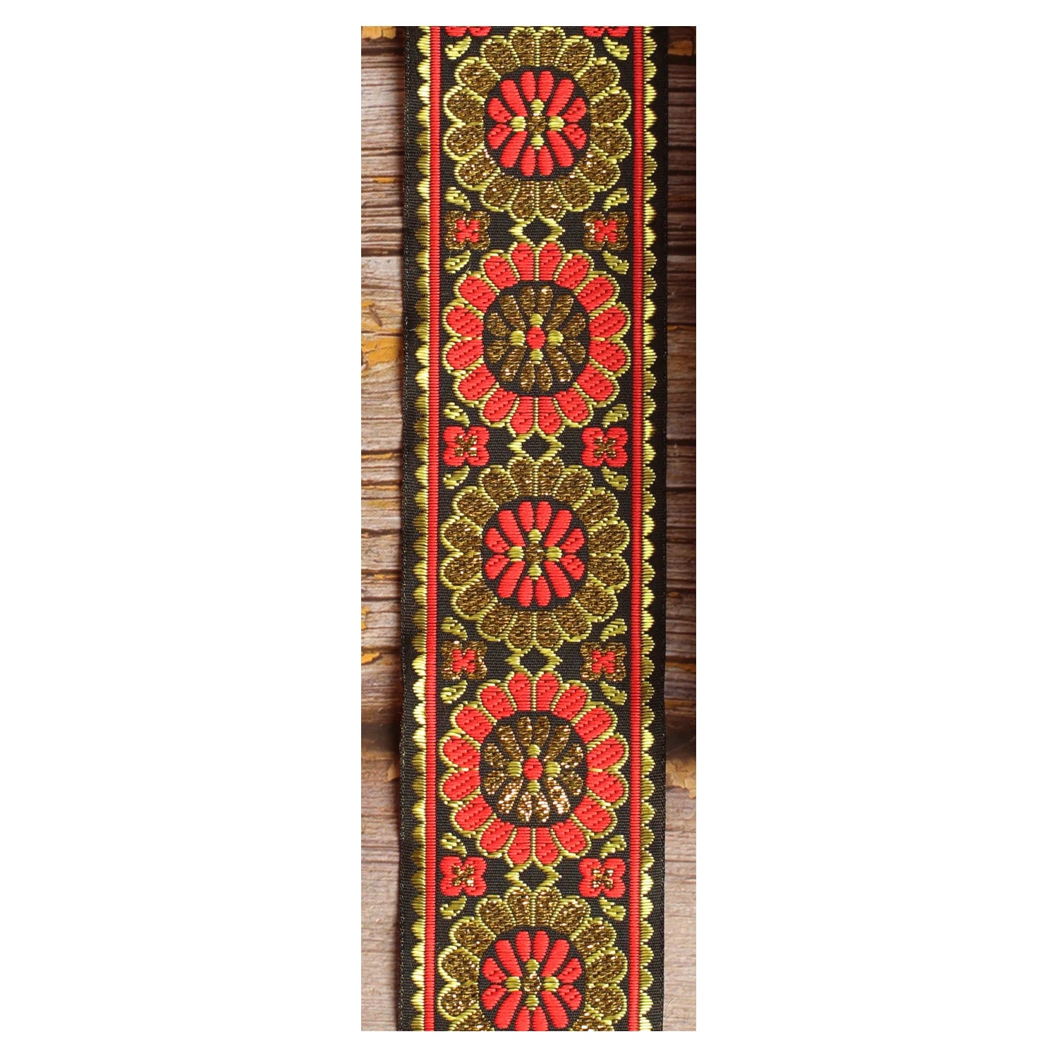 Amber Parade woven guitar strap featuring warm orange and golden botanical motifs against a black background.