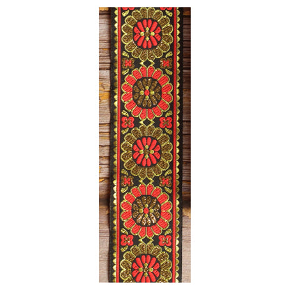 Amber Parade woven guitar strap featuring warm orange and golden botanical motifs against a black background.