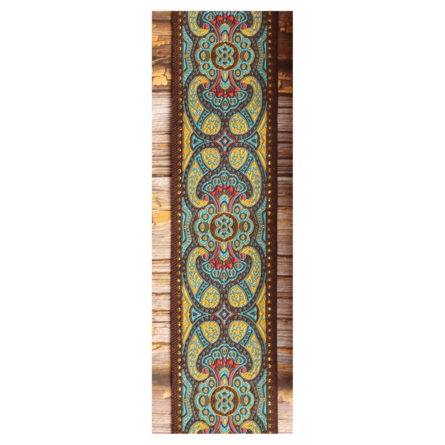 Close-up of the Blue Lake guitar strap design with symmetrical turquoise, golden and red details against a dark brown background.
