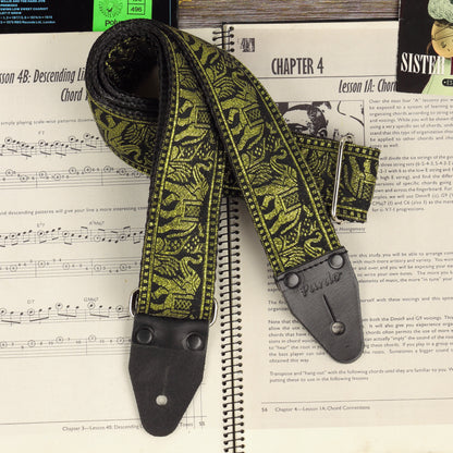Close-up of the Black and Gold elephant jacquard guitar strap with black leather ends on a sheet music book