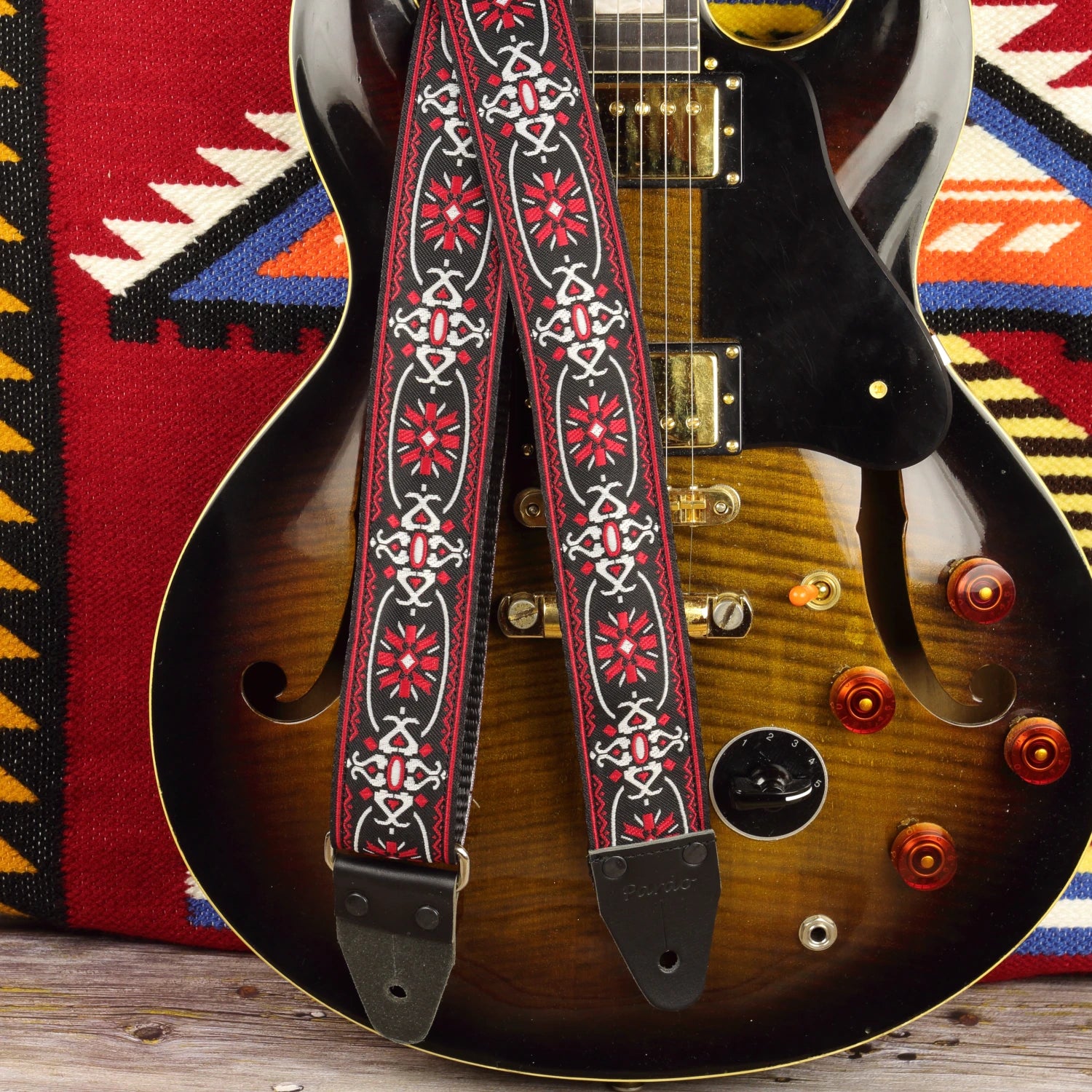 Blackdoor guitar strap displayed with an Aria ES-500 semi-hollow guitar, showing its red, white and black woven design.