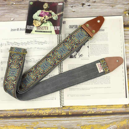 Full view of the Blue Garden guitar strap on a sheet music book, showing its jacquard pattern, leather ends and Gray suede backing.