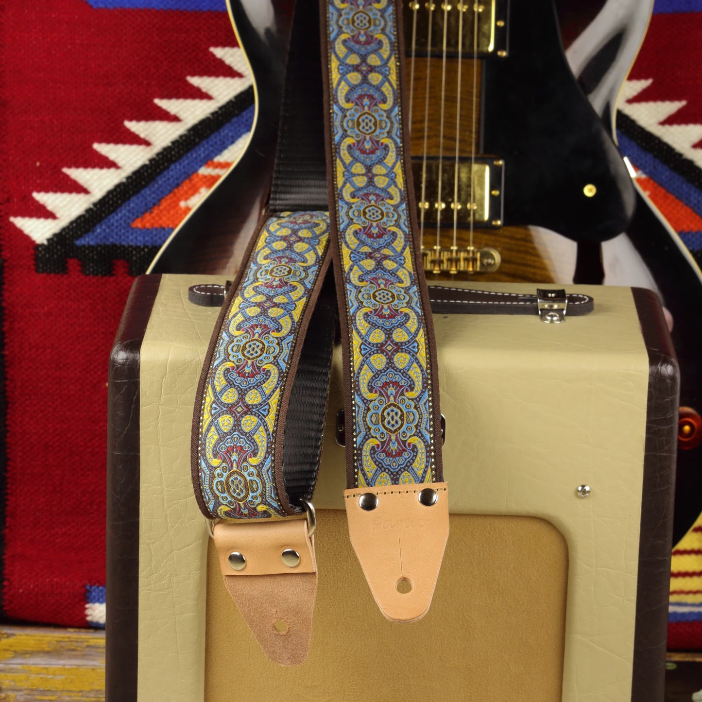 Blue lake guitar strap displayed with a Fender Champion 600 amplifier and electric guitar in the background.