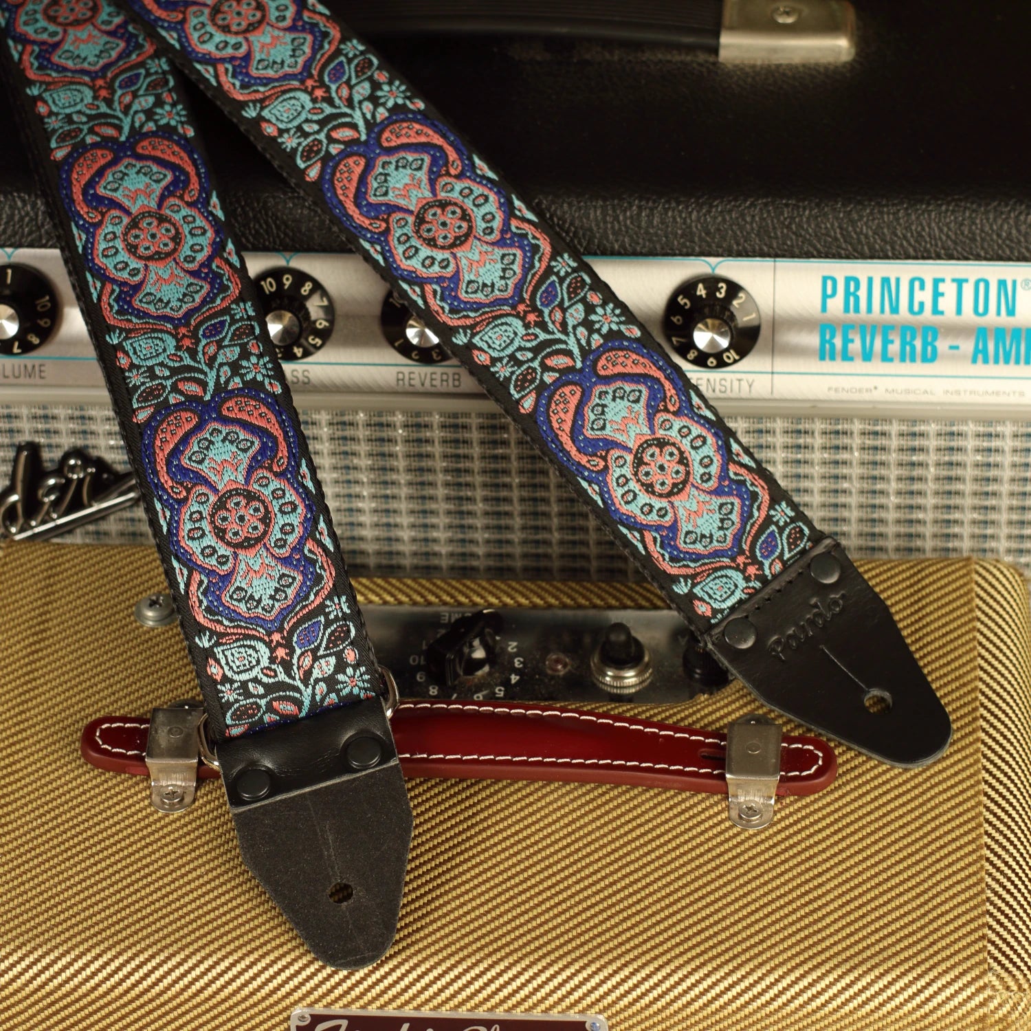 Close-up of the Blue Mirage handmade guitar strap showing genuine leather ends with Fender Princeton Reverb and Fender Champ amplifiers
