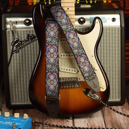 Blue Mirage handmade guitar strap featuring an intricate jacquard pattern displayed on a sunburst Fender Stratocaster with a Fender Princeton Reverb amplifier