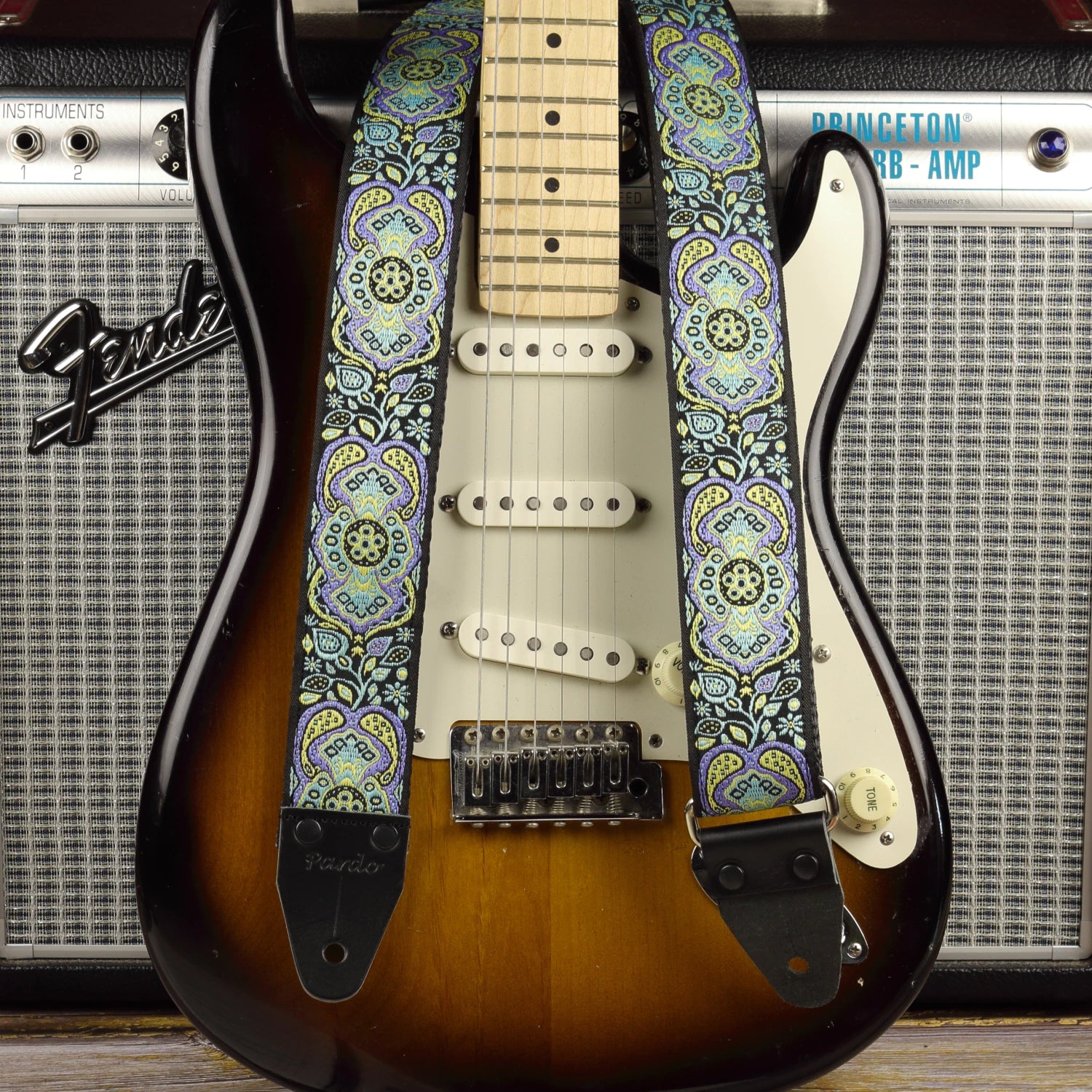 Blue Paisley guitar strap displayed with a sunburst Fender Stratocaster and a Fender Princeton Reverb amplifier.
