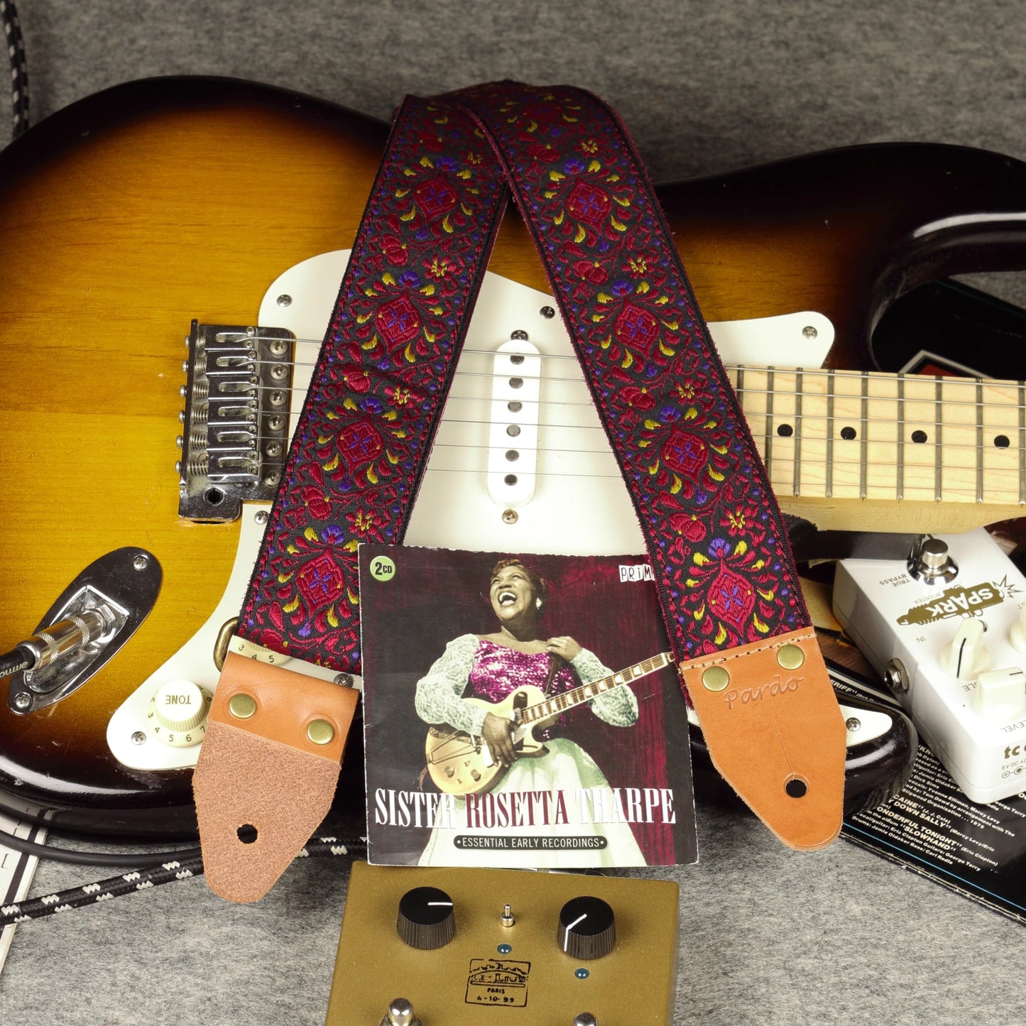 Burgundy Pheasant guitar strap on a Sunburst Fender Stratocaster in a studio setting with guitar pedals and a Sister Rosetta Tharpe CD cover