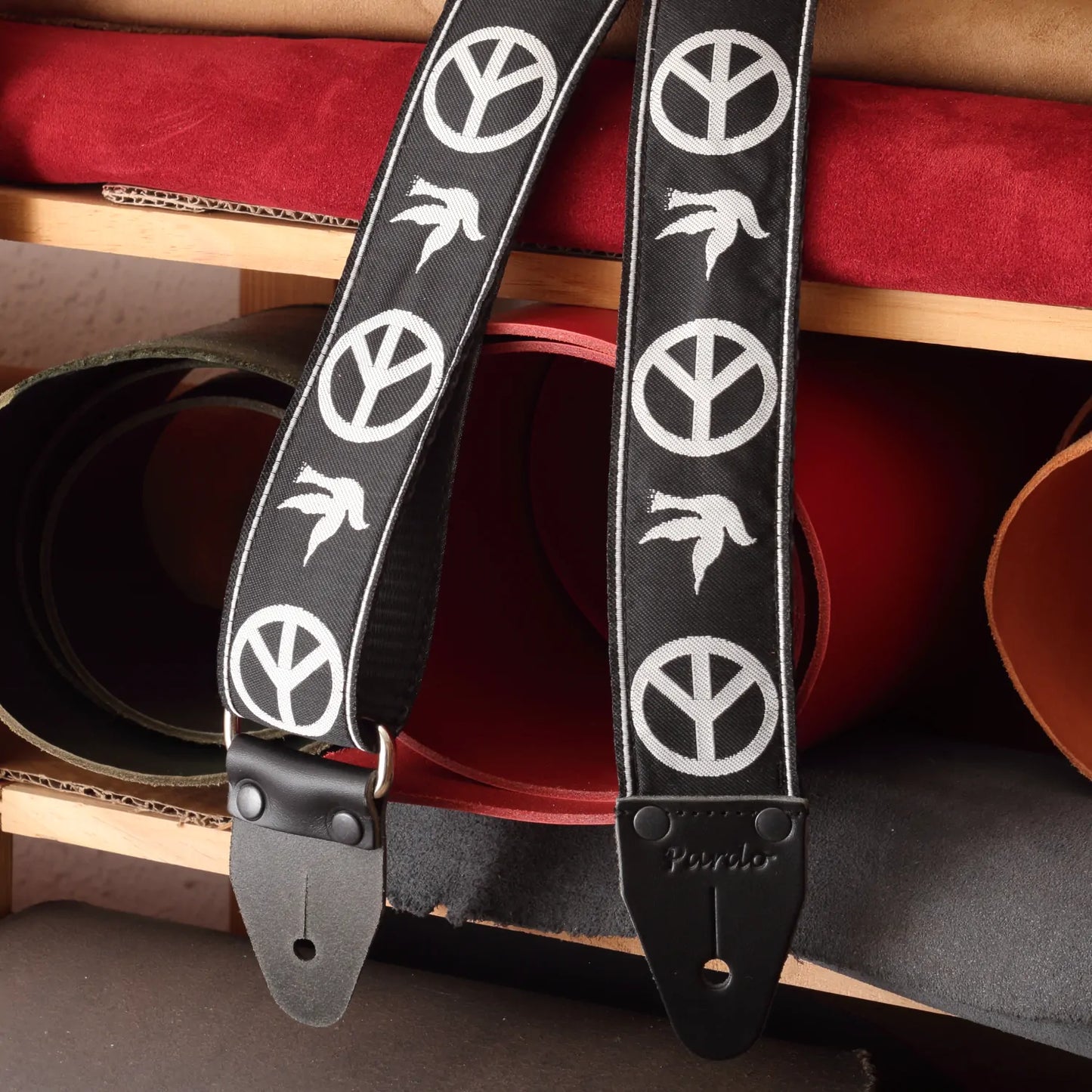 Finished dove guitar strap displayed alongside the raw leather end pieces and jacquard fabric