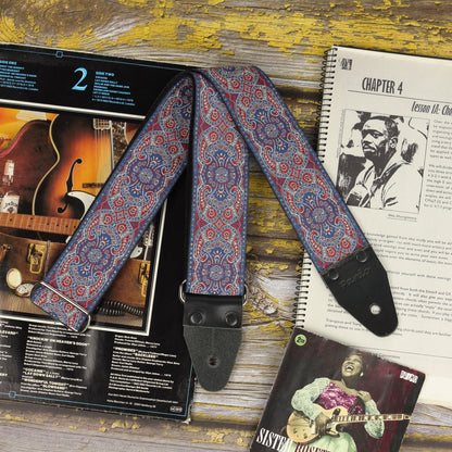 Close-up of the Efrit guitar strap with black leather ends, displayed with sheet music and vinyl records.