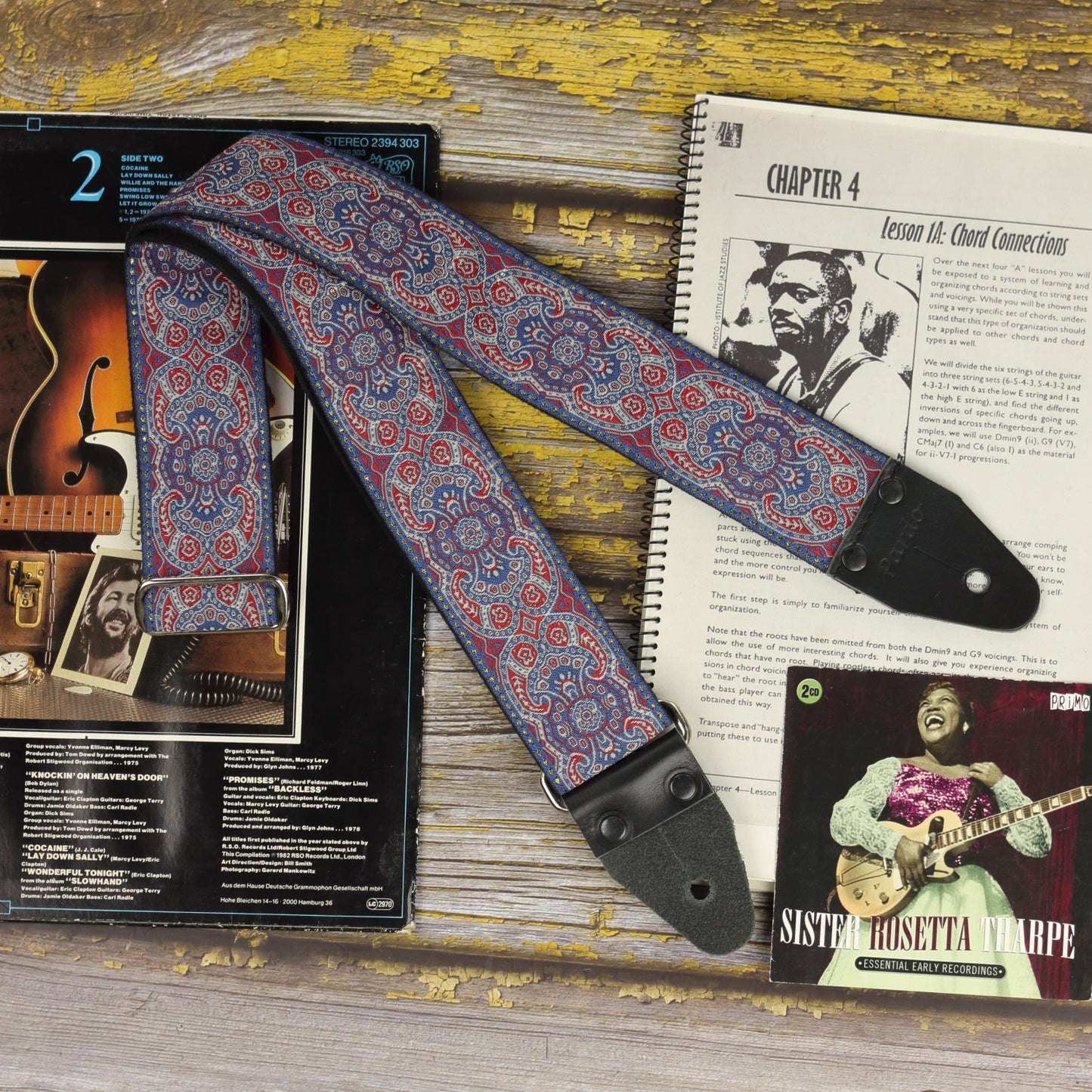 General view of the Efrit guitar strap displayed with a sheet music book and vinyl records.