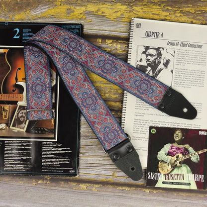 General view of the Efrit guitar strap displayed with a sheet music book and vinyl records.