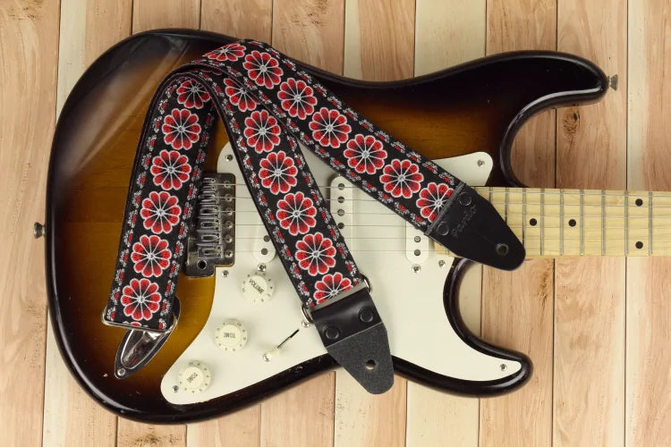 Black background guitar strap decorated with vibrant red floral patterns and a classic vintage aesthetic.