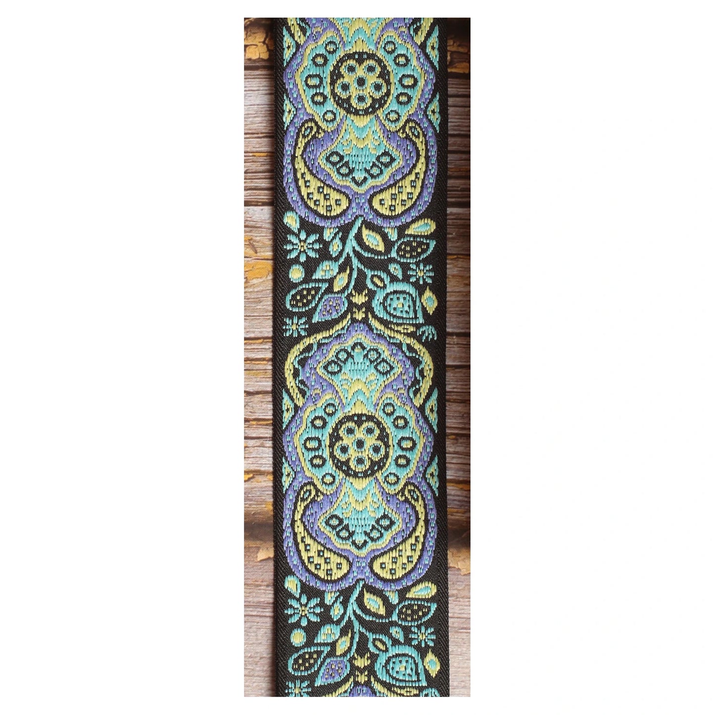 Close-up of the Blue Paisley guitar strap design with large turquoise, pale yellow and lavender motifs against a black background.
