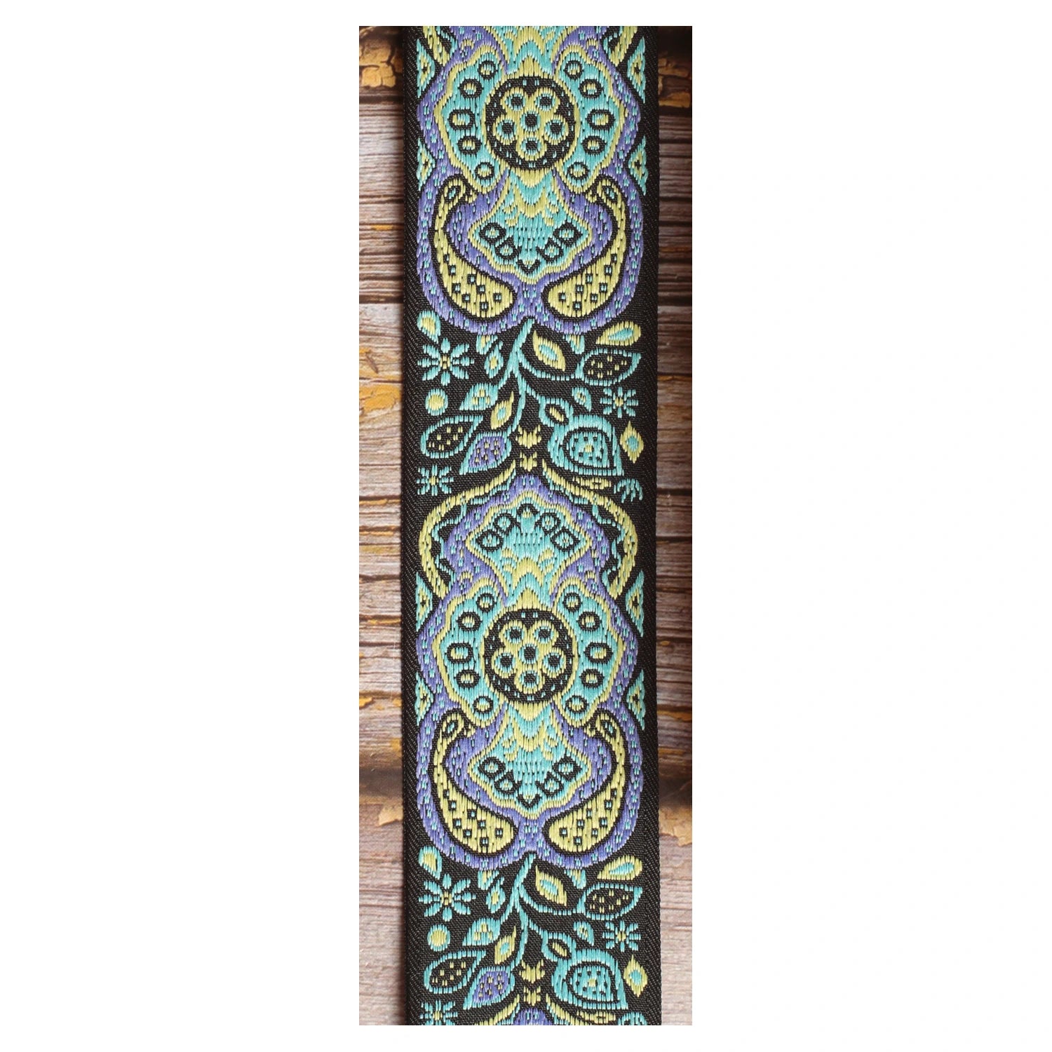 Close-up of the Blue Paisley guitar strap design with large turquoise, pale yellow and lavender motifs against a black background.
