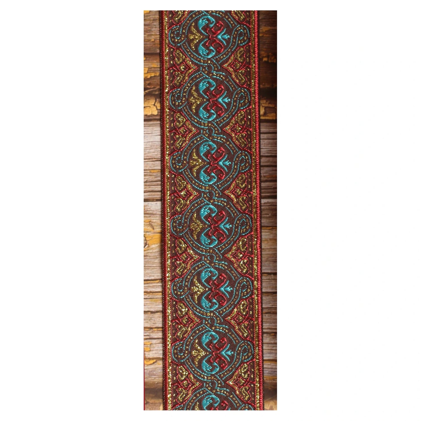 Close-up of the Pilgrim guitar strap design with interlocking turquoise and red forms, golden details and deep red borders.