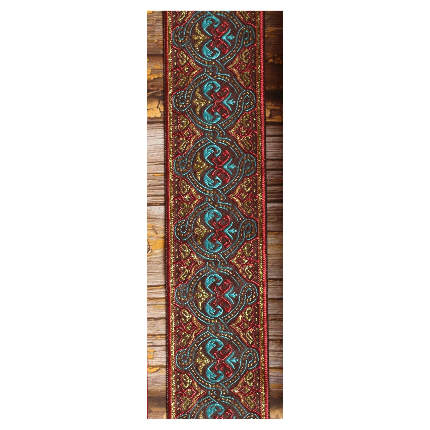 Close-up of the Pilgrim guitar strap design with interlocking turquoise and red forms, golden details and deep red borders.