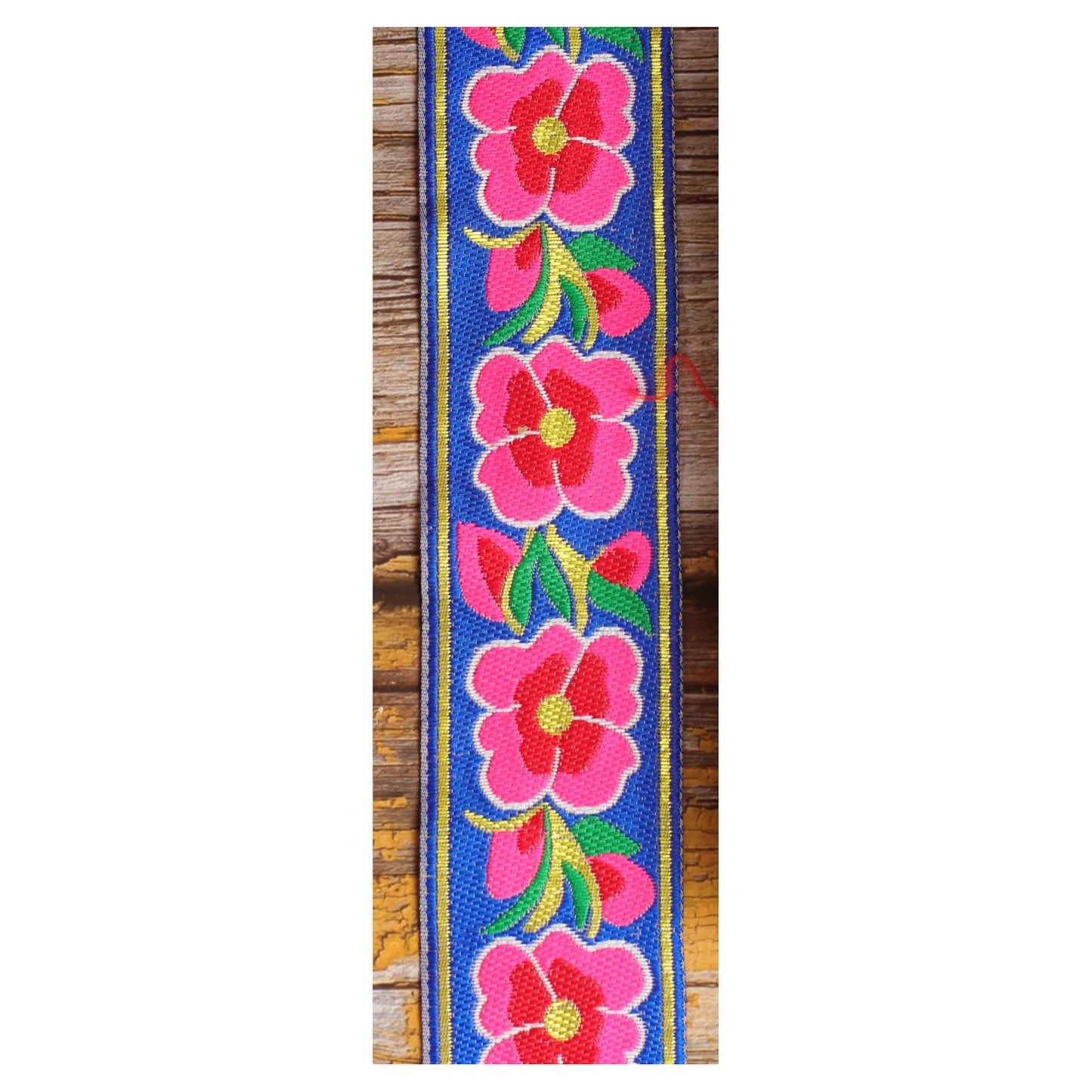 Close-up of the Blue Serenade guitar strap design with large pink and red motifs and green leaves against a rich blue background.
