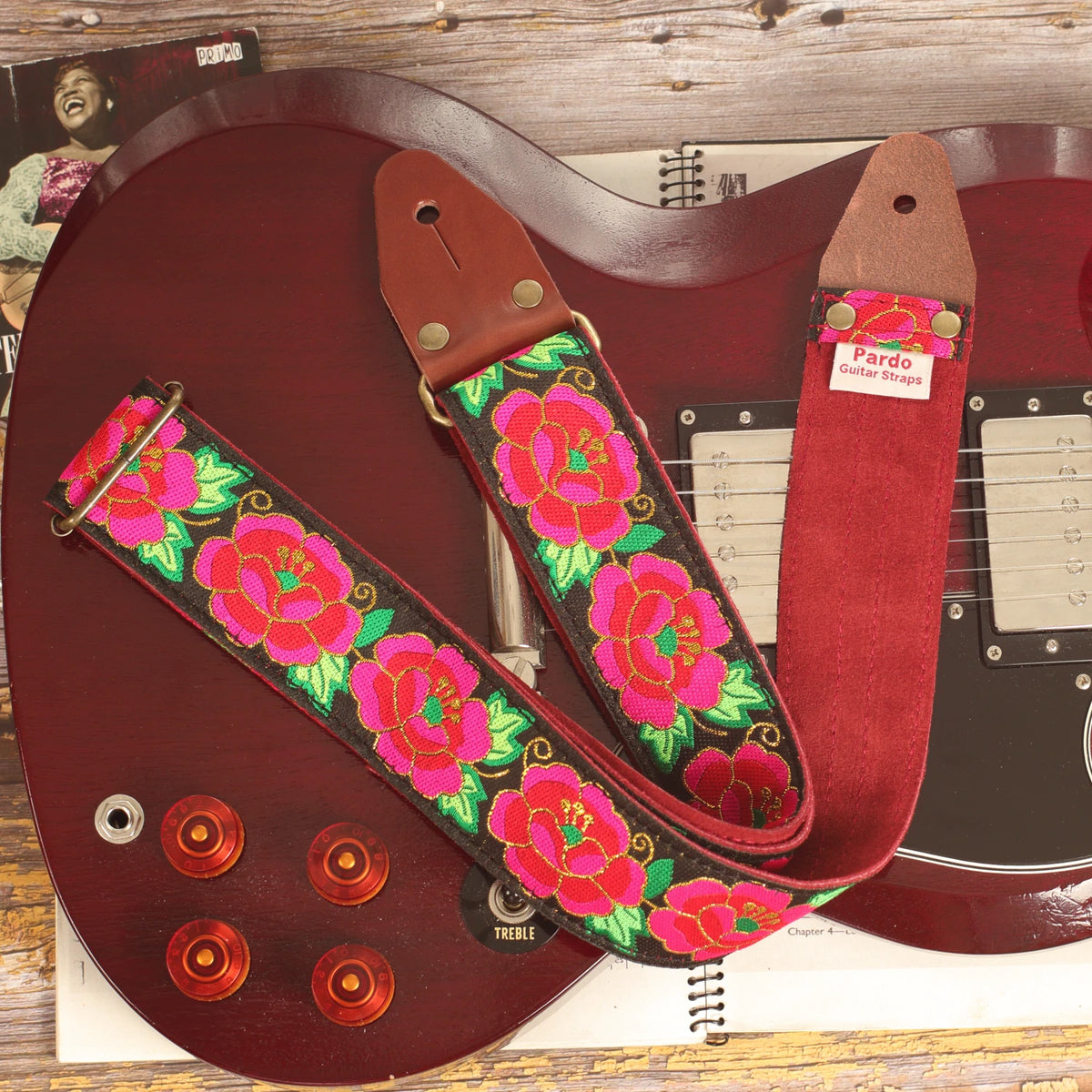Close-up of the Grand Petal Red Roses guitar strap on an Edwards SG-style guitar, showing the Red Burgundy suede backing