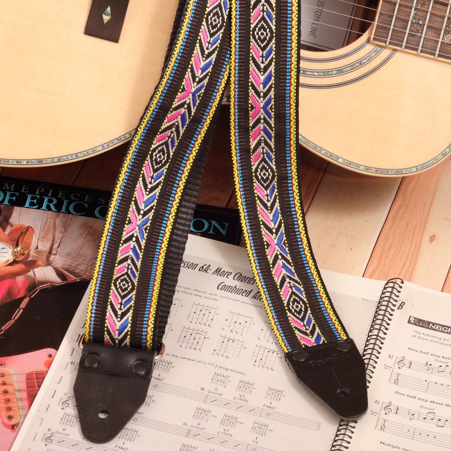 The strap attached to an acoustic guitar, showcasing the colorful design against natural wood tones.