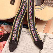 The strap attached to an acoustic guitar, showcasing the colorful design against natural wood tones.