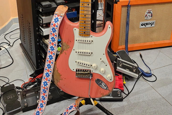 Fender Stratocaster displayed in a music studio with an Eric Clapton-inspired floral guitar strap.