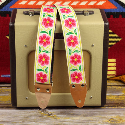 Ivory Garland guitar strap displayed on a Fender Champion 600 amplifier, showing its large red and pink woven motifs against an ivory background.