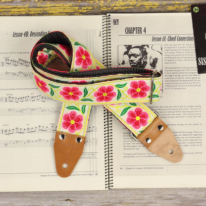 Rolled Ivory Garland guitar strap displayed on a sheet music book, showing its woven design and light brown leather ends.