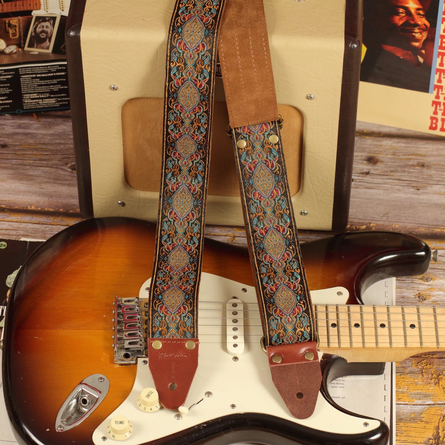 Loyalty multicolored jacquard guitar strap displayed with a Fender Stratocaster Sunburst and Fender Champion 600 amplifier in a studio-inspired setting.