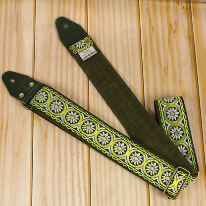 Close-up of the Meadow Echo strap showing its woven pattern, green leather ends and Green Moss suede backing on a wooden surface.