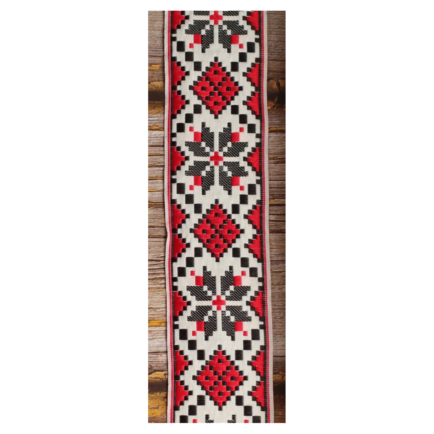 Close-up of the Crimson Compass guitar strap design with symmetrical red and black geometric motifs on an ivory background.