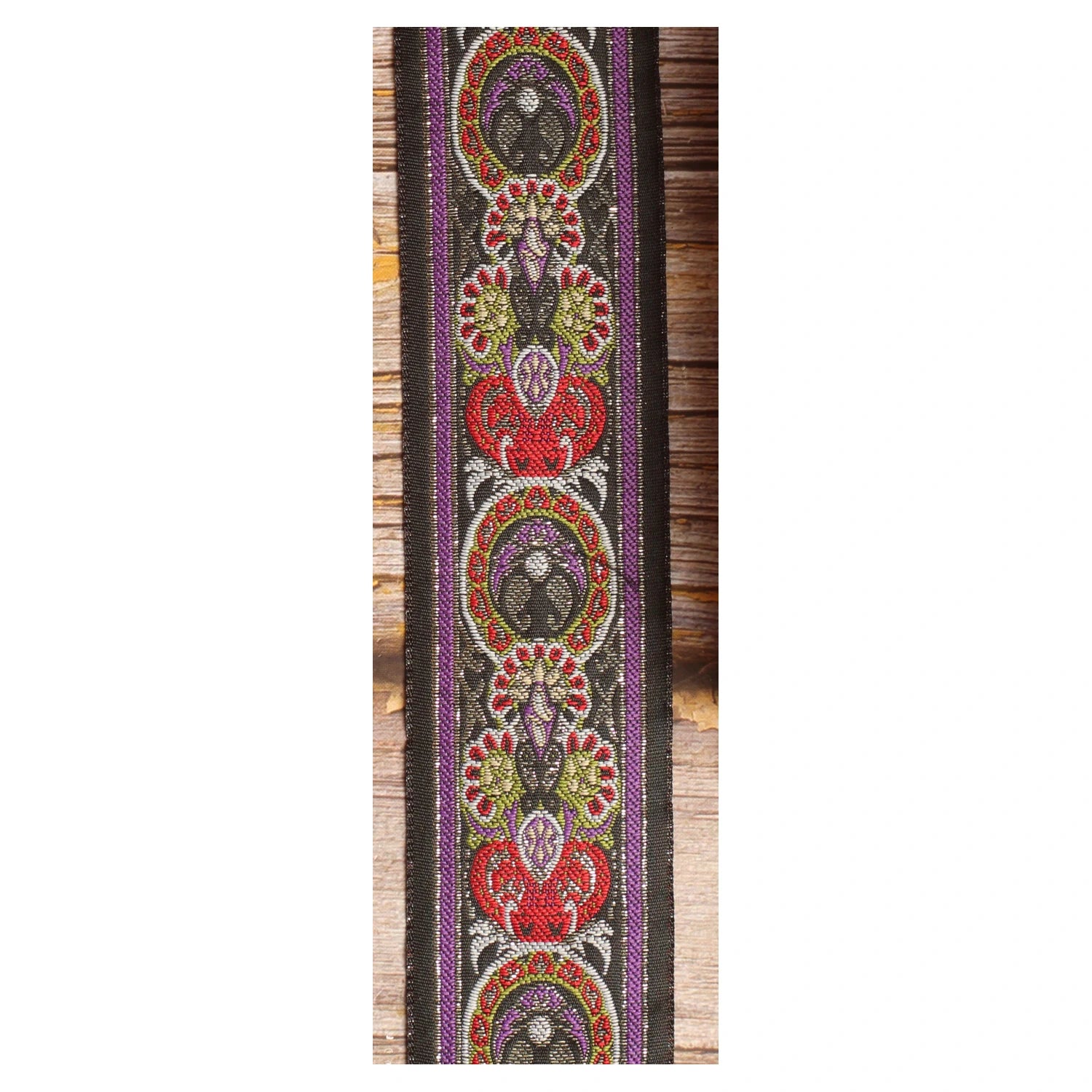 Close-up of the King guitar strap design with framed red, purple, green and ivory ornamental forms against a dark background.