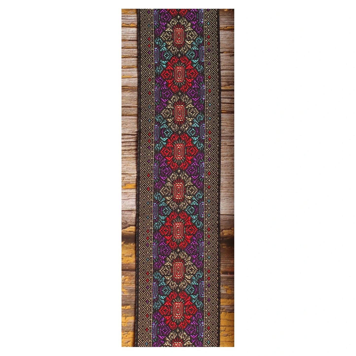 Close-up of the Purple Frame guitar strap design featuring intricate red, purple and turquoise motifs with metallic details on a dark background.