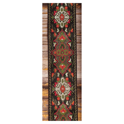 Close-up of the Red Fly guitar strap design with symmetrical red, olive green, ivory and orange details against a black background.