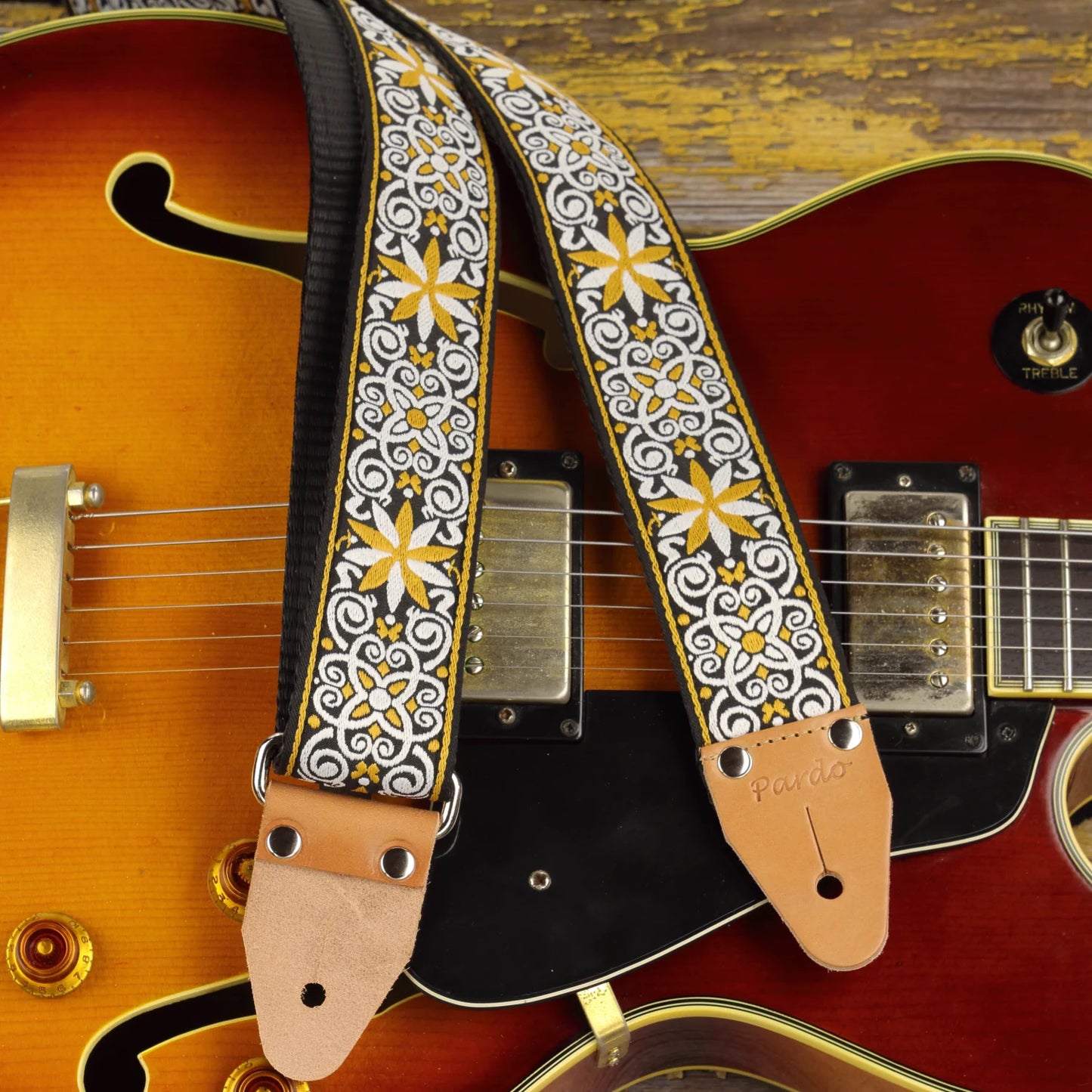 Ocher and white mosaic guitar strap paired with a hollow body jazz guitar, featuring a structured geometric pattern with intricate woven detail.