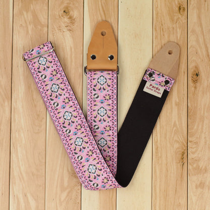 Pink Pheasant guitar strap showing the woven jacquard front and seatbelt backing on a wooden background