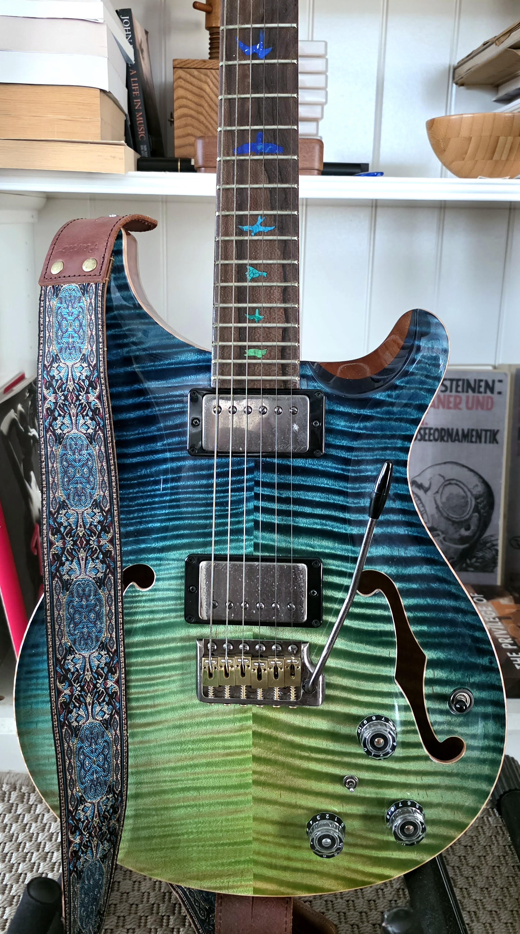 PRS Hollowbody II Piezo with tremolo in Caribbean Dragon’s Breath, featuring colorful stone bird inlays and a matching Pardo guitar strap.