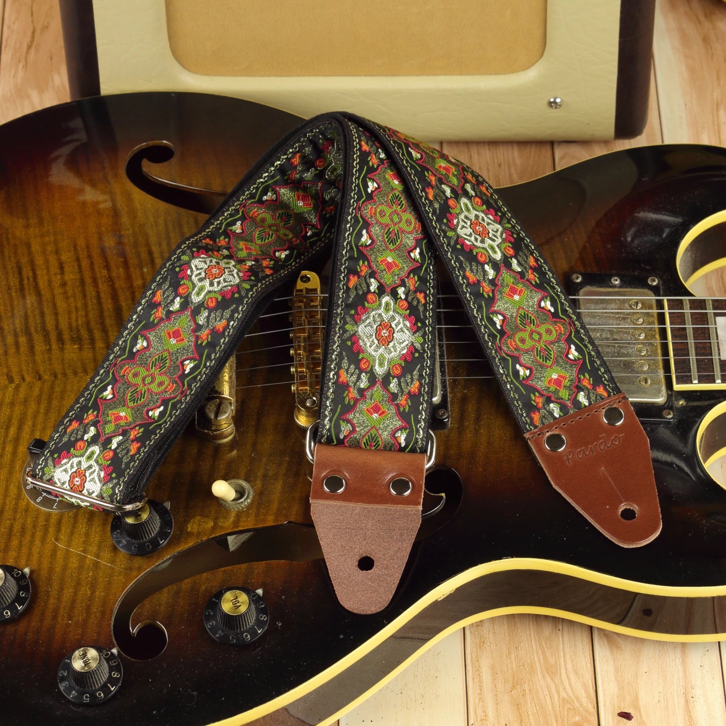 Red Fly guitar strap displayed on an Aria ES-500 semi-hollow guitar, showing its red, olive green and ivory pattern.