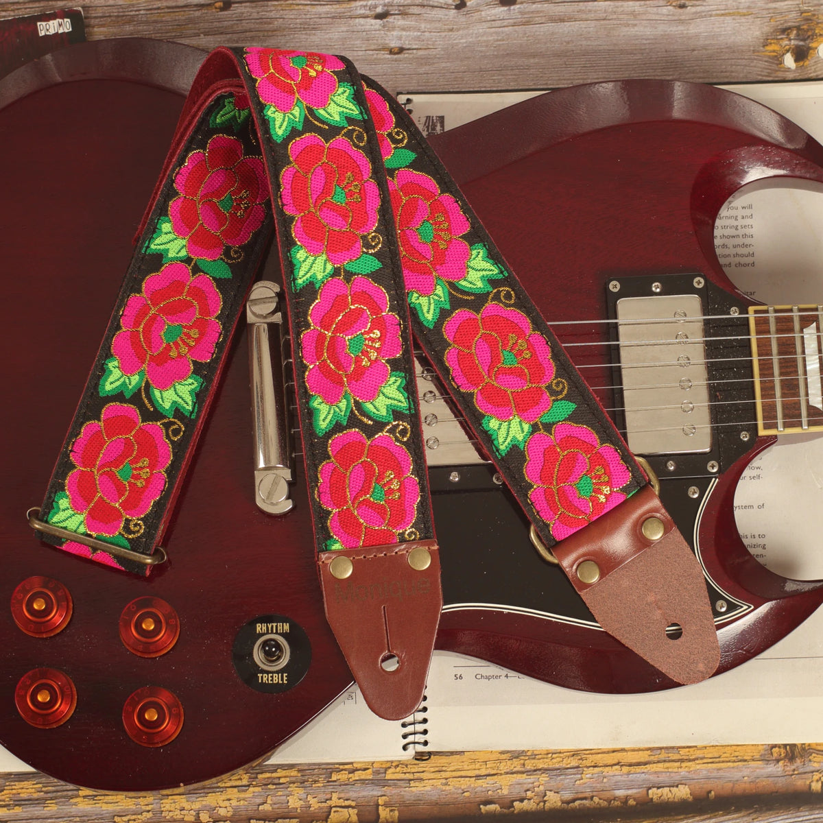 Rose-pattern guitar strap displayed on a cherry red Edwards SG-style guitar