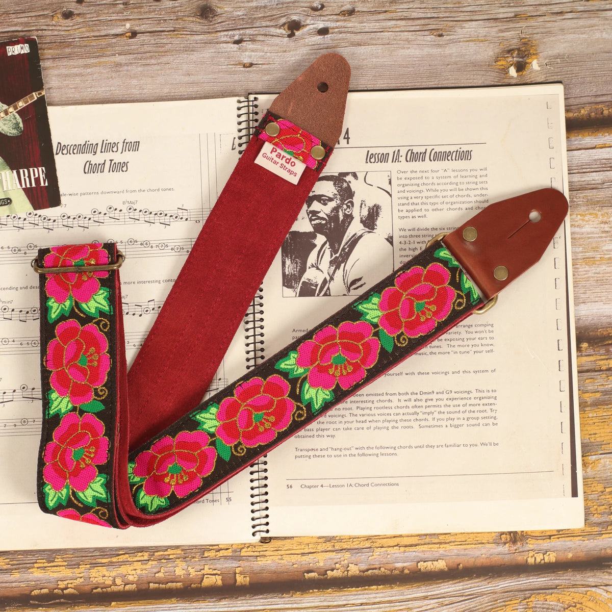 Roses guitar strap on a sheet music book with Red Burgundy suede backing