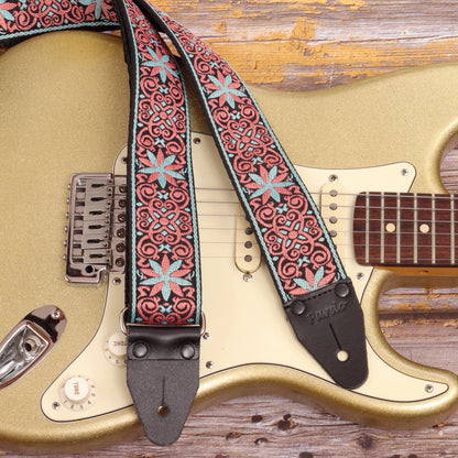Salmon and light blue mosaic guitar strap displayed with a Fender Stratocaster, highlighting a dense geometric pattern and flowing visual rhythm.