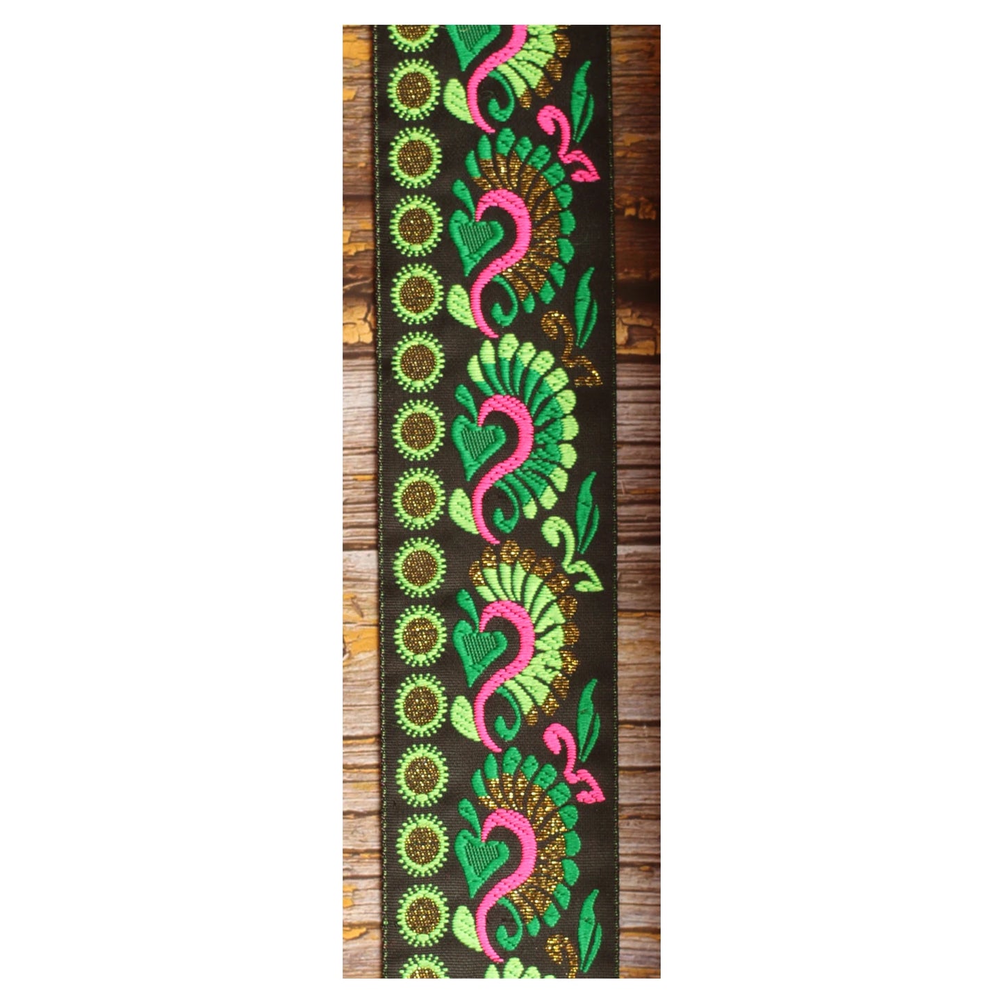 Close-up of the Swann Green guitar strap design with flowing green and pink motifs and golden details on a black background.