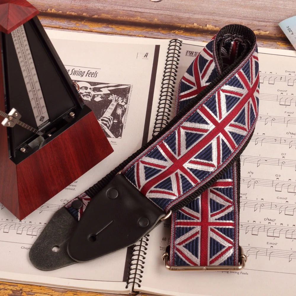 wide long guitar strap with UK flag design next to metronome and sheet music